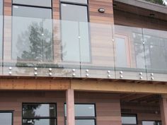 there is a balcony with glass railings on the side of this building and trees in the background