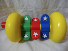 three plastic toys with stars on them sitting on a white sheeted surface, one yellow and the other red