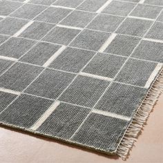 a gray rug with white squares and fringes