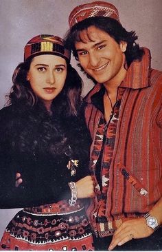 a man and woman are posing for a photo in traditional clothing, one is wearing a headdress while the other wears a turbana