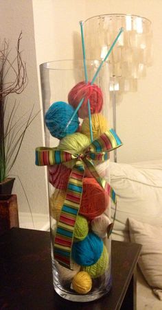 a vase filled with balls of yarn on top of a table next to a couch