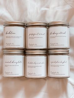 six jars of candles sitting on top of a white sheet