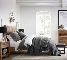 a bedroom with white walls and grey bedding