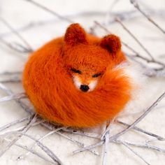 an orange stuffed animal laying on top of a white surface next to some branches and twigs