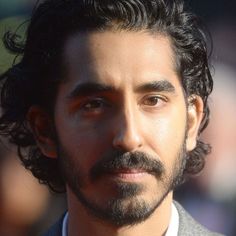 a close up of a person wearing a suit and tie with dark hair, beard and mustache