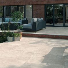 an outdoor patio with couches and potted plants in front of the glass doors