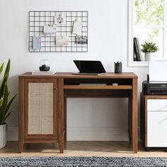 a wooden desk with a laptop on top of it next to a potted plant