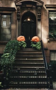 two pumpkins sitting on the steps of a brownstone building