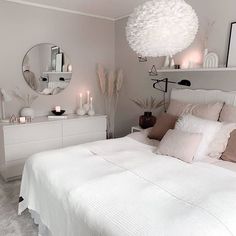 a white bed sitting in a bedroom next to a dresser with candles on top of it