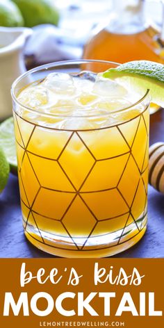 a close up of a drink in a glass on a table with limes and honey