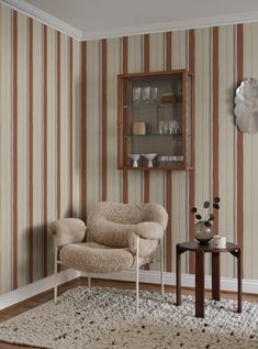 a living room with striped wallpaper and a chair in front of a small table