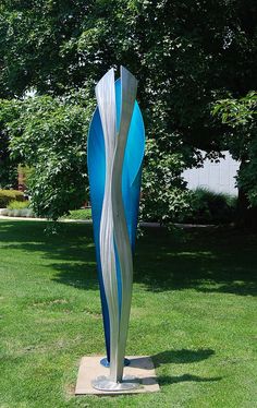 a blue and white sculpture sitting on top of a lush green field