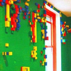 there is a green wall with legos all over it and a red window in the corner