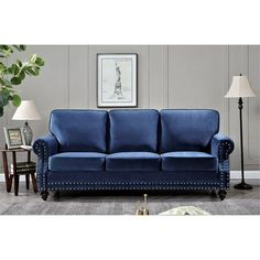 a blue couch sitting on top of a wooden floor next to a table and lamp