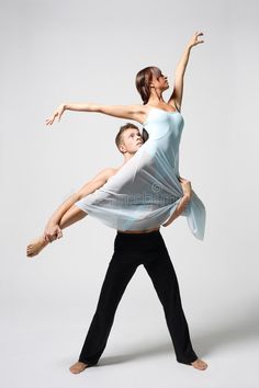 a man and woman are dancing together in the middle of an artistic dance pose with their arms stretched out