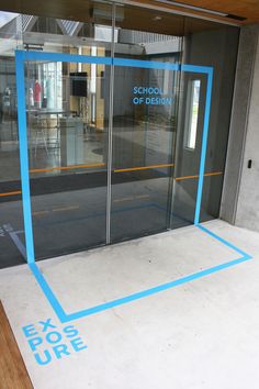 the entrance to an office building with glass doors and blue tape on the floor that says exosure