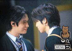 two young men in school uniforms are looking at each other's eyes and smiling