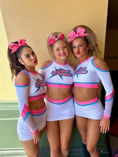 three girls in cheerleader outfits posing for the camera