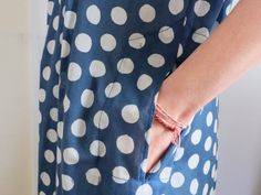 a woman wearing a blue and white polka dot dress with her hands on the pocket