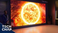 a man standing in front of a large television screen with an image of the sun on it