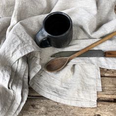 a cup and spoon sitting on top of a white cloth next to a wooden spoon