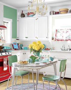 a kitchen filled with lots of white cabinets and green chairs next to a red stove top oven