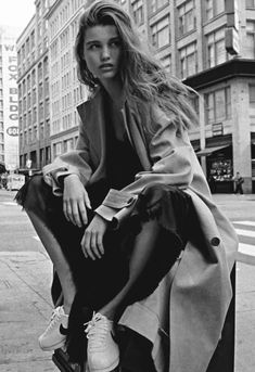 a black and white photo of a woman sitting on a pole