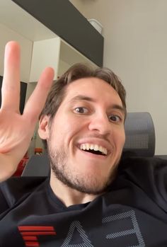 a man is making the peace sign with his hand while sitting in an office chair