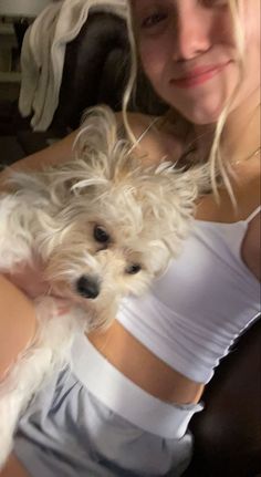 a woman holding a small white dog in her arms