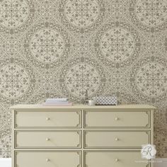 a white dresser sitting next to a wall with a flower pattern on the top and bottom