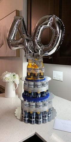 a birthday cake made out of beer bottles and foil balloons with the number forty on top