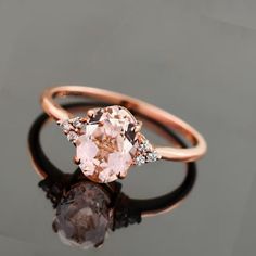 an oval shaped morganite and diamond ring on a reflective surface