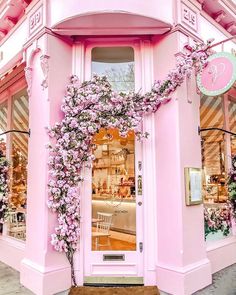 a pink store front with purple flowers on the door and in the window, there is a sign that says love