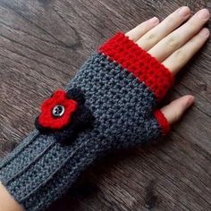 a woman's hand wearing a gray and red knitted glove with a flower on it