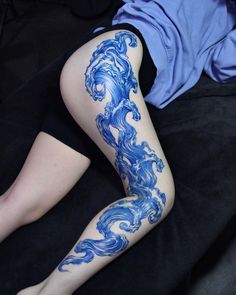 a woman laying on top of a bed covered in blue ink next to her legs