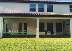 the back of a house with two people sitting on the porch and one person standing outside