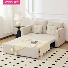 a white couch sitting on top of a rug next to a table with a lamp