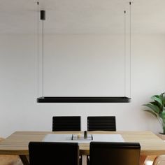 a dining room table with black chairs and a plant hanging from the ceiling over it