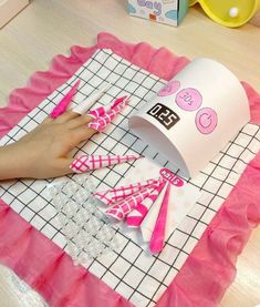 a person is cutting paper with scissors on top of a pink and white table cloth