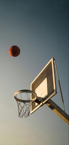 a basketball flying through the air next to a net with a ball on it's backboard