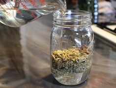 a person pours water into a jar filled with herbs