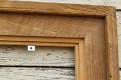 a close up of a wooden frame with a small hole in the middle on a wall