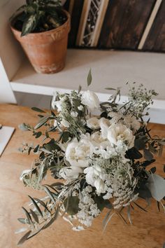 a vase filled with white flowers on top of a wooden table