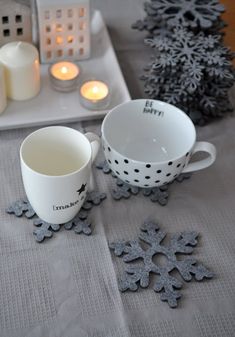 two cups on a table with candles and snowflakes