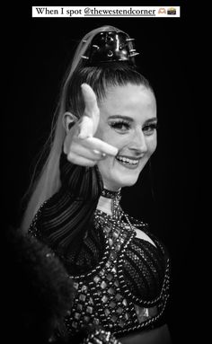 a black and white photo of a woman in costume giving the peace sign with her hand