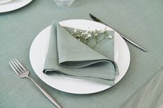 a table set with napkins, silverware and flowers on top of the plate