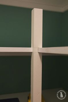 there is a cross made out of wood in the corner of a room with green walls