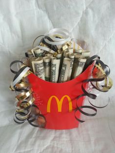 a red bucket filled with money sitting on top of a white sheet