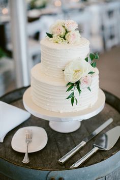 a wedding cake sitting on top of a wooden table next to silverware and forks