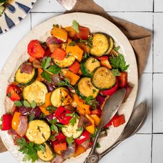 a white plate topped with lots of veggies next to a fork and knife